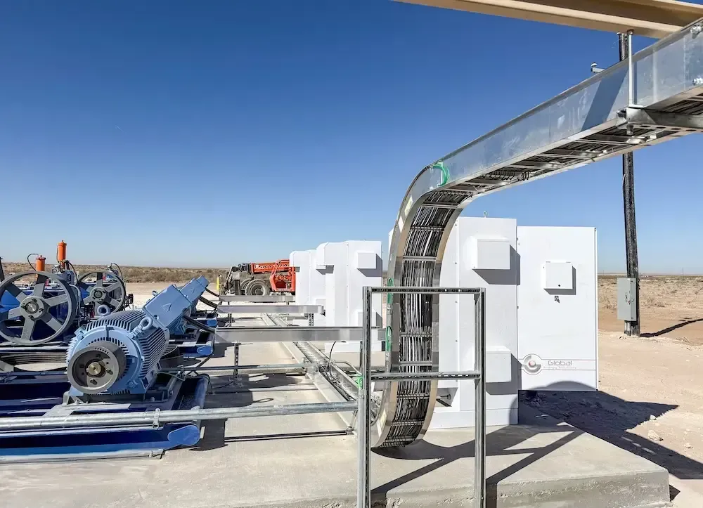Industrial machinery and conveyor system at a desert facility under a clear blue sky
