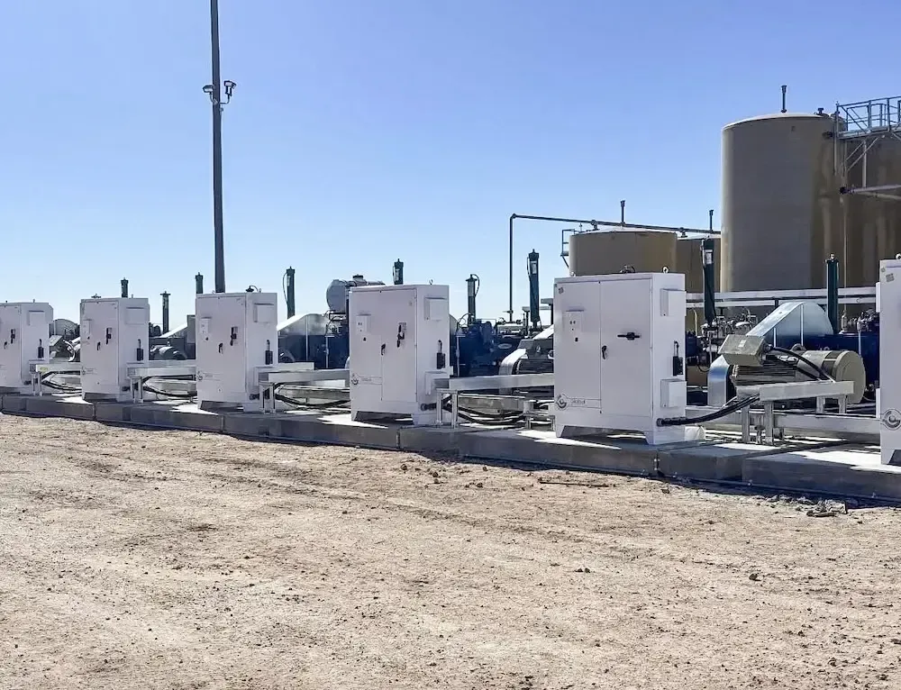 White industrial equipment units lined up on a dusty lot under a clear blue sky.