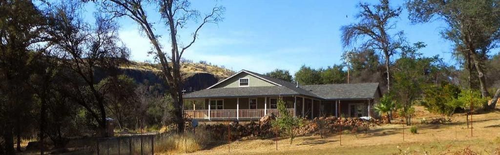 A house is sitting in the middle of a field surrounded by trees.