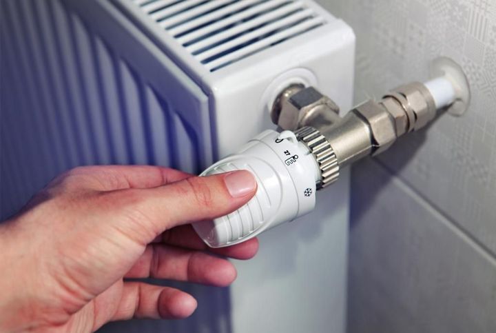 A person is adjusting a thermostat on a radiator.