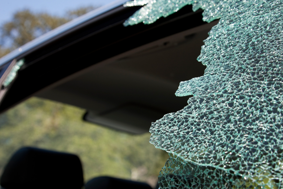 A car with a broken windshield is parked on the side of the road.