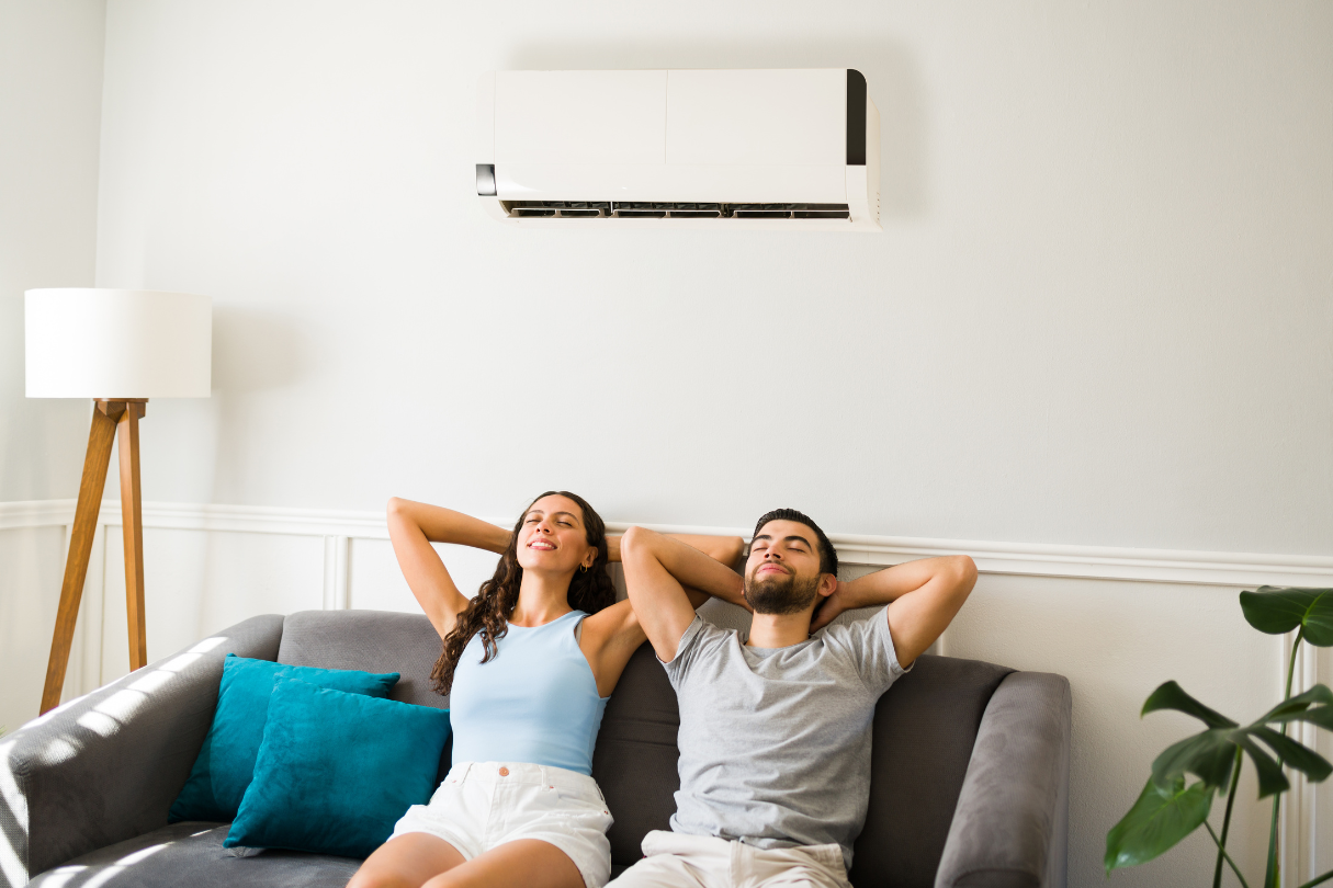 A man and a woman sitting on a couch with their hands behind their heads, enjoying the comfort of solar film in San Antonio on nearby windows.