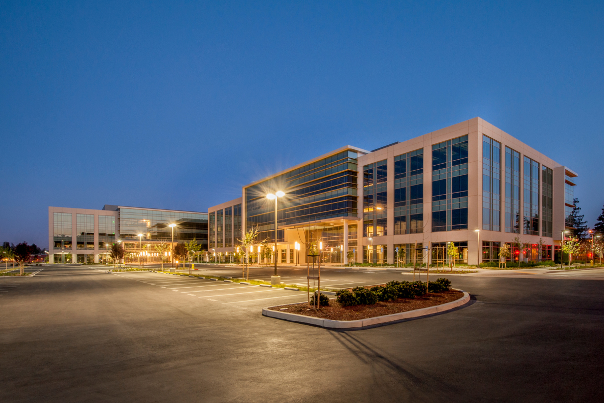 A large building with many windows lit up at night, protected with security tint.