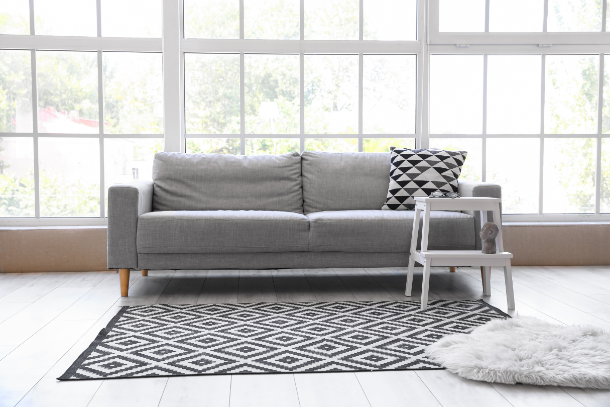 A living room with a gray couch and a black-and-white rug, featuring solar film for windows in San Antonio.