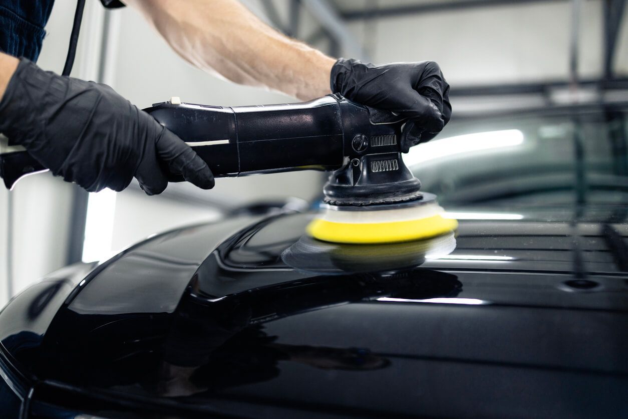A man works on a car window, demonstrating a step in the window tint removal process.
