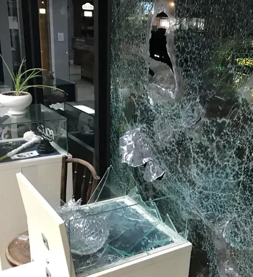 A broken glass window with a display case in front, illustrating the need for security tint.