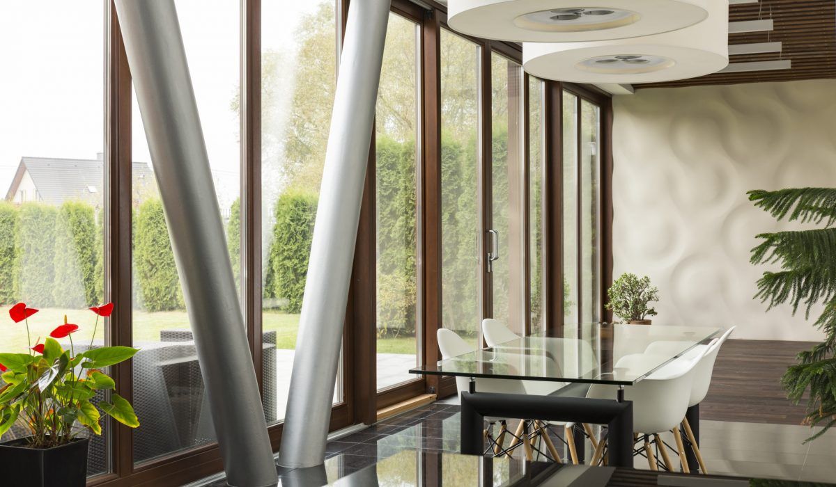 A dining room with a glass table and chairs and lots of windows