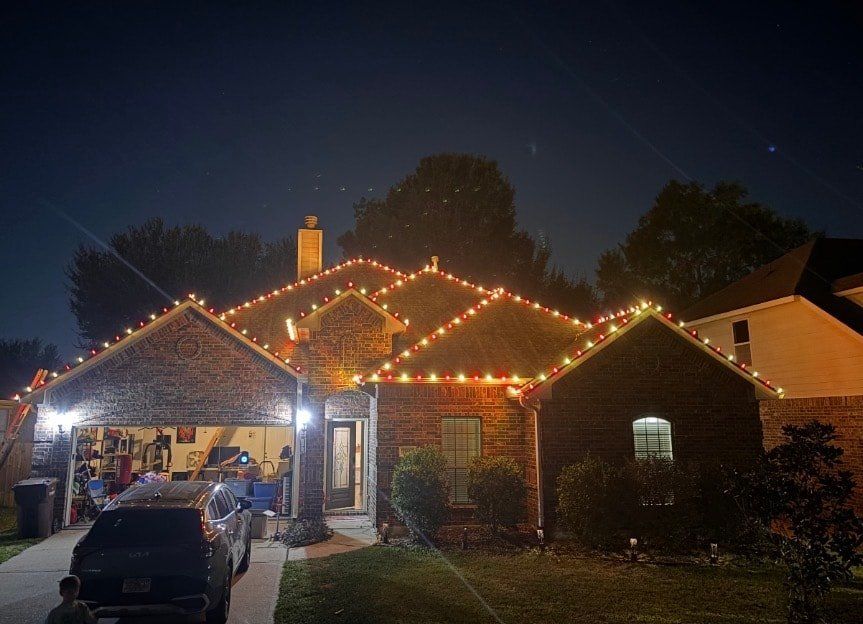 Red and gold C9 bulbs running the full roofline of a brick ranch home