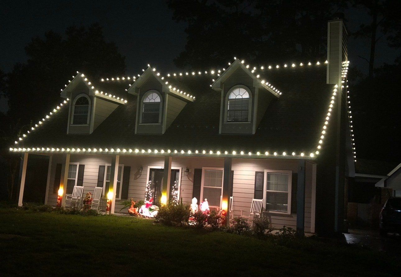 Warm white C9 bulbs traced along the roofline and gables of a two-story home