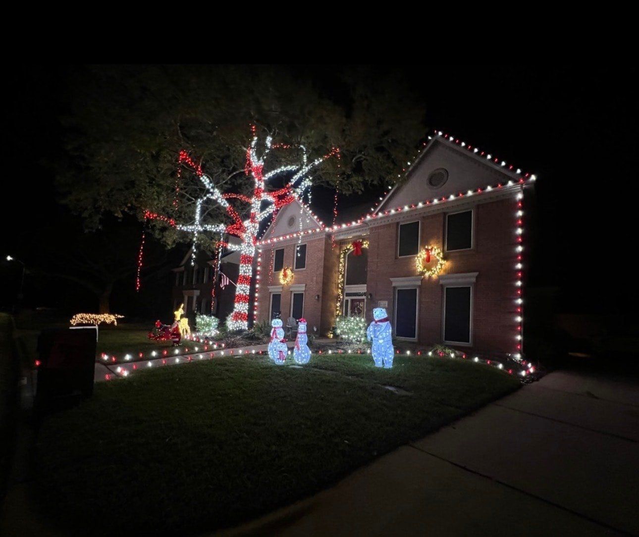 Full holiday display with roofline bulbs, candy canes and lit snowmen on the lawn