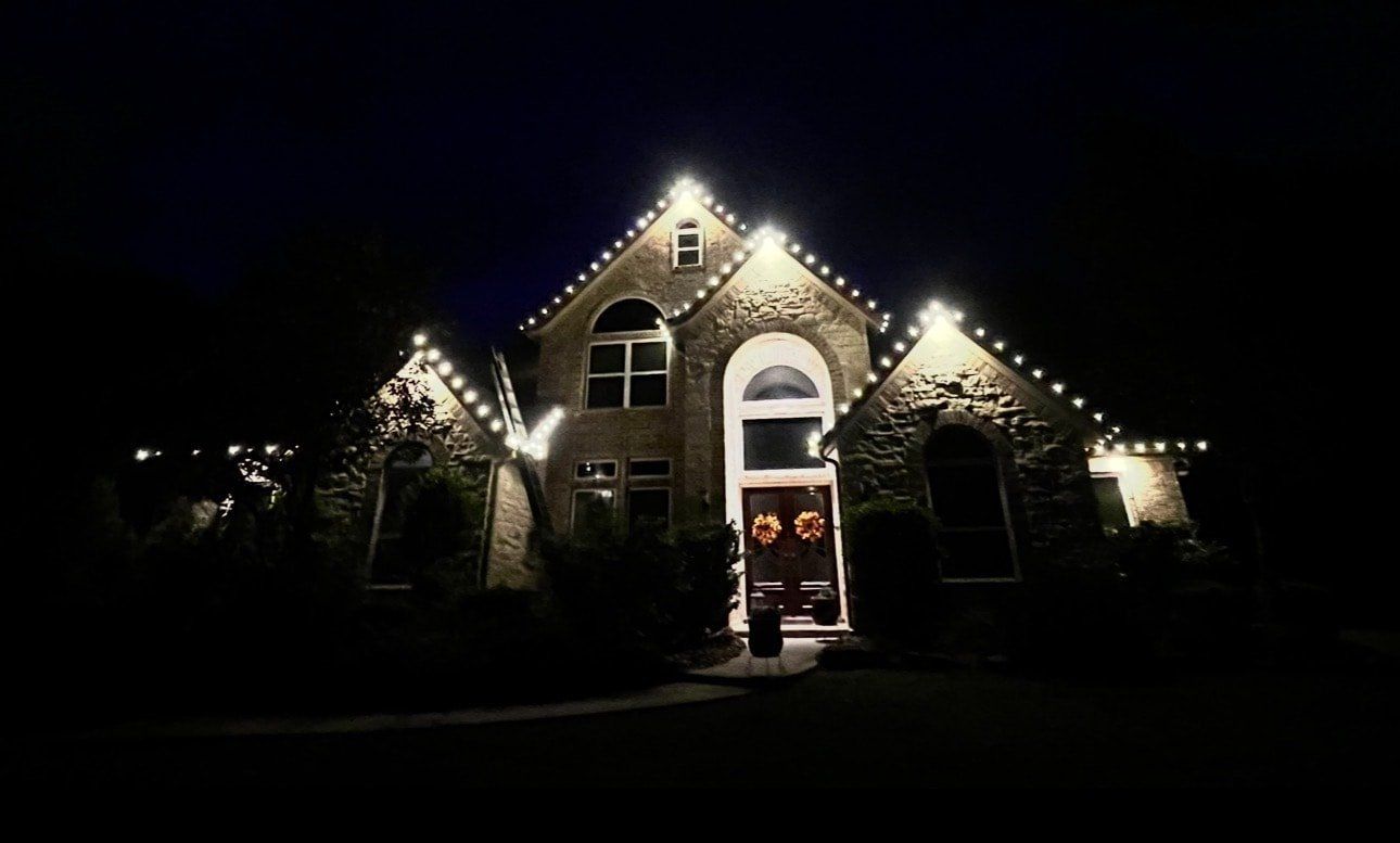 Stone home outlined in warm white C9 bulbs against a dark sky