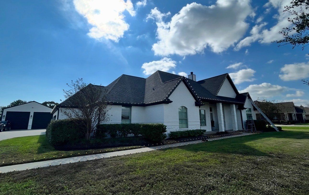 Daytime view of a white home with C9 bulb line installed along the roof edge