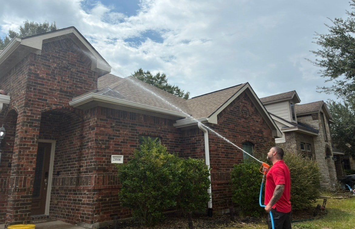 An Elite Exterior Cleaning owner soft washing the brick and siding of a two-story home in North Houston