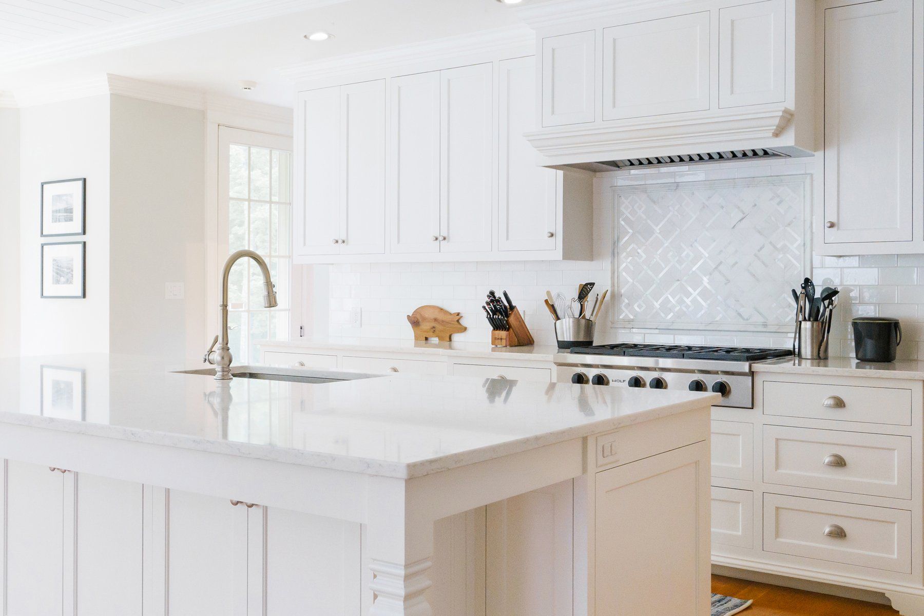 Bright white modern kitchen with island, farmhouse sink, and stainless steel stove
