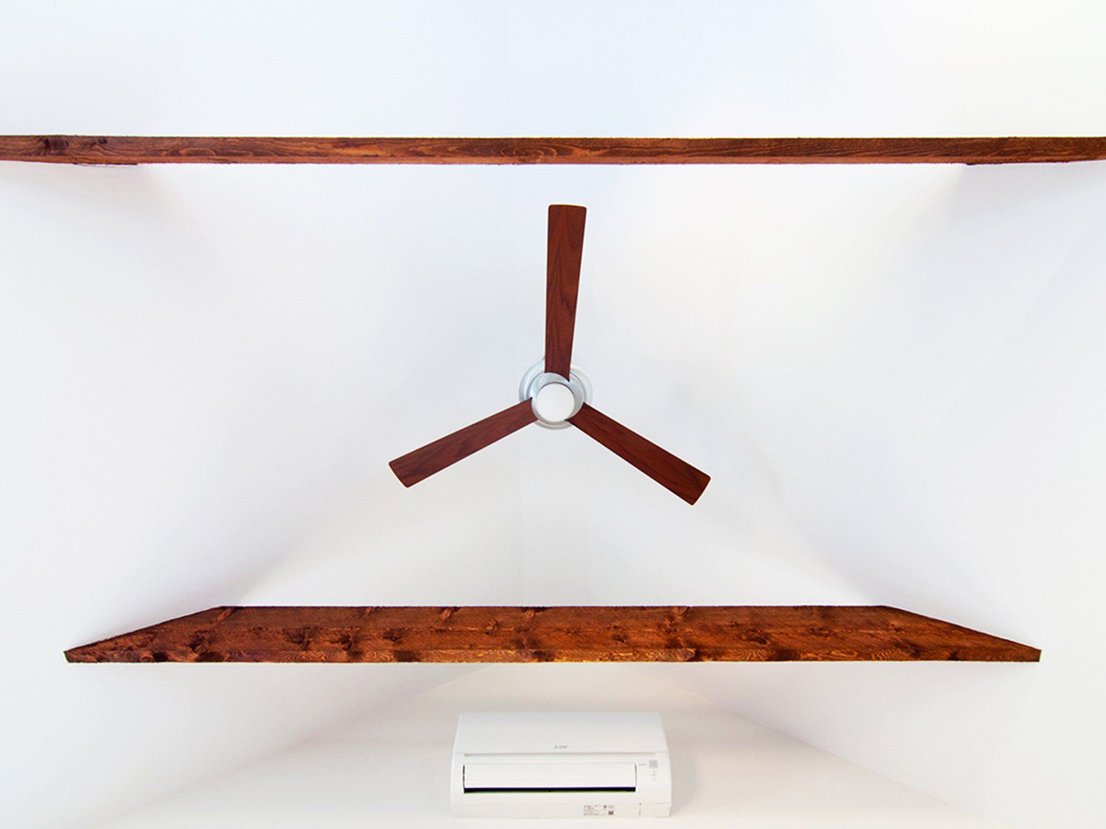 Minimalist room with rusted floating shelves and a three-blade ceiling fan centered on a white wall