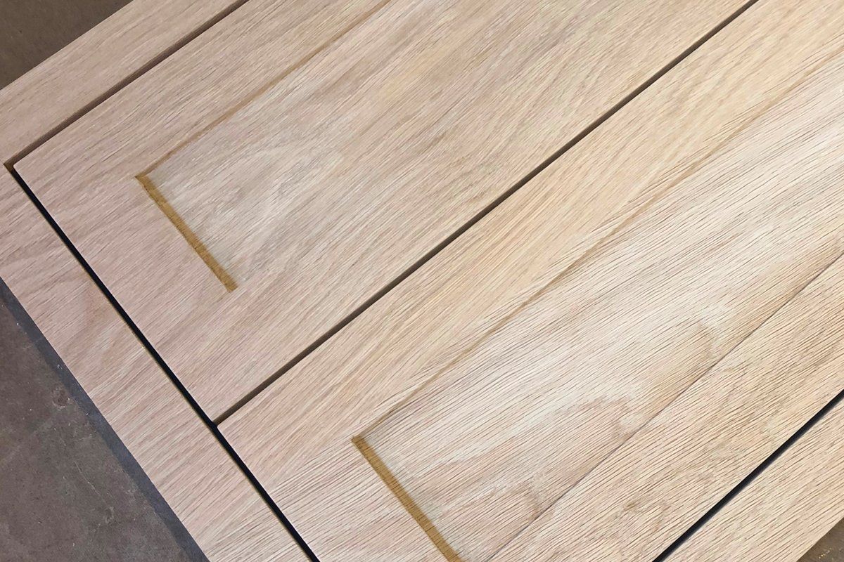 Close-up of two light wood cabinet drawers with gold handles on a dark countertop