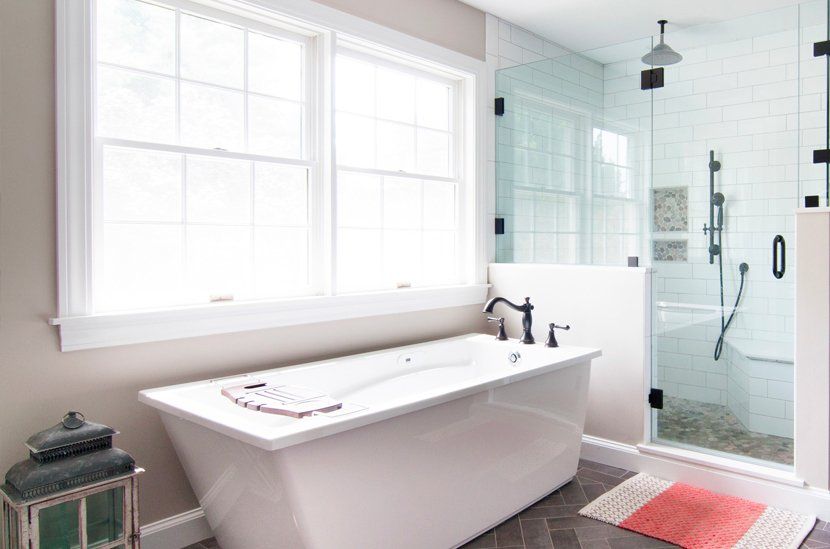 Bright bathroom with freestanding tub, glass shower, and large windows