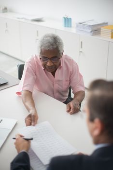 Dos personas revisando documentos en una mesa en una oficina luminosa.