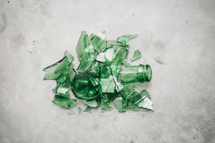 Pile of broken green glass bottles on a concrete surface