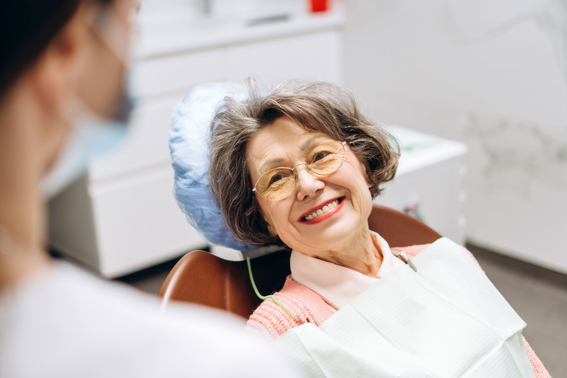 A person smiles while sitting in a dental chair during an appointment.