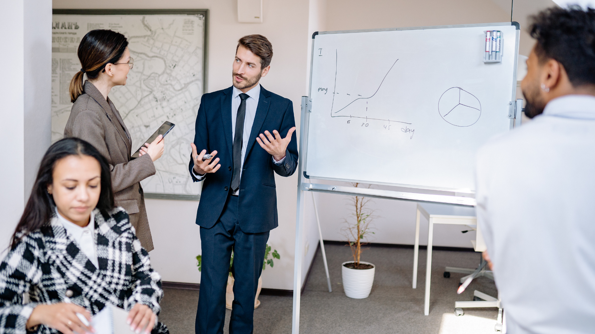Business meeting with people discussing ideas near a whiteboard in an office meeting room