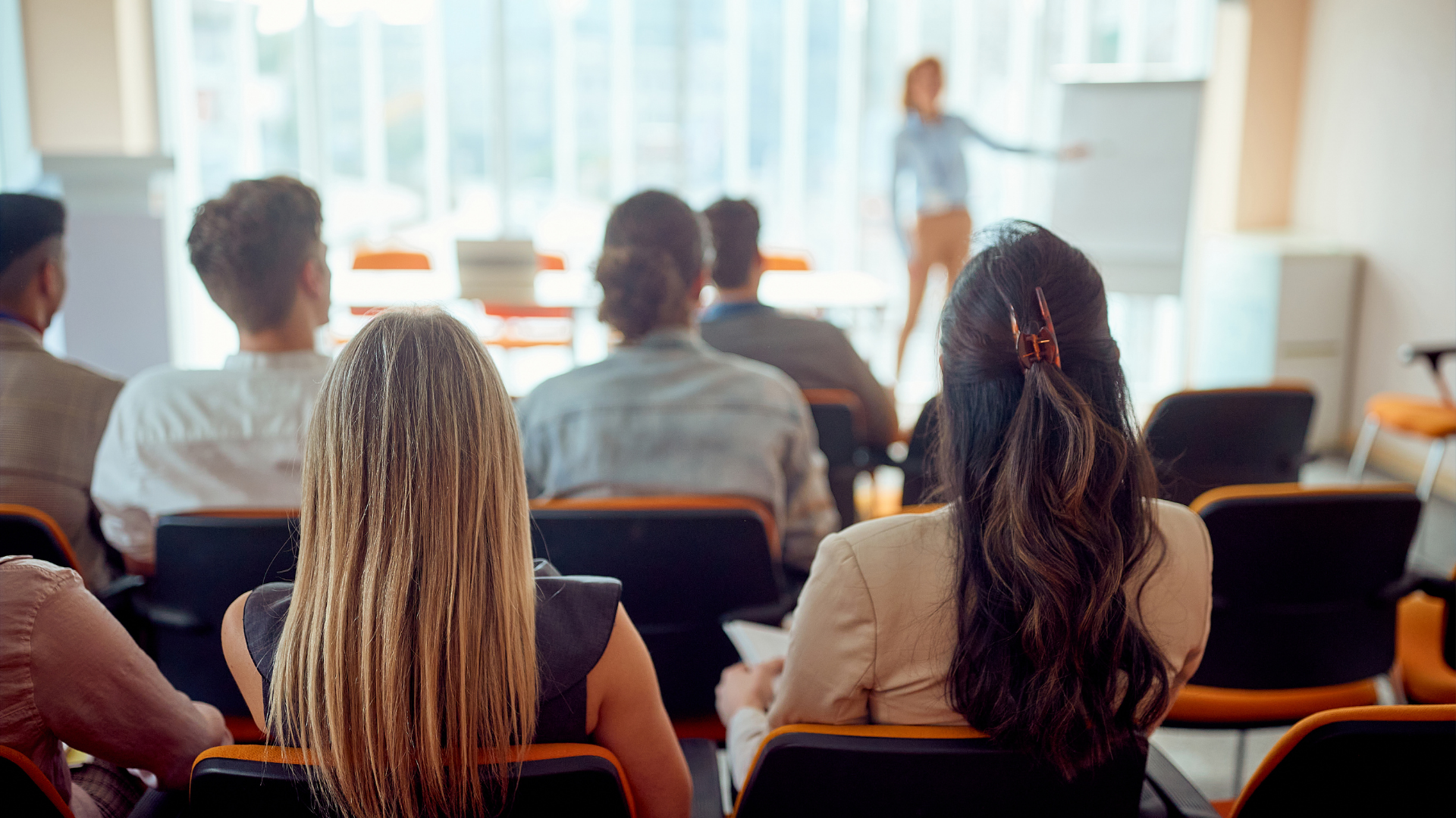 Audience seated in a lecture hall facing a presenter at the front