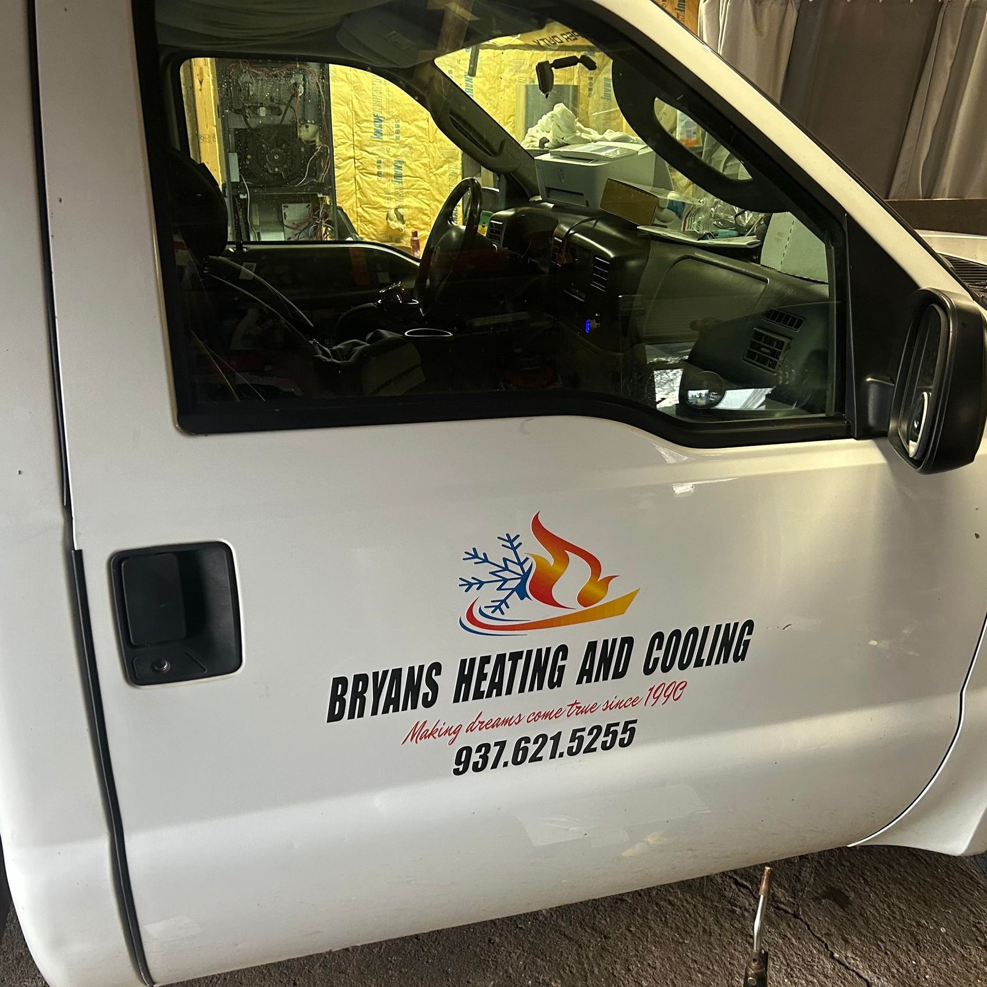 The side door of a white service truck featuring the Bryans Heating and Cooling logo and phone number, 937.621.5255.