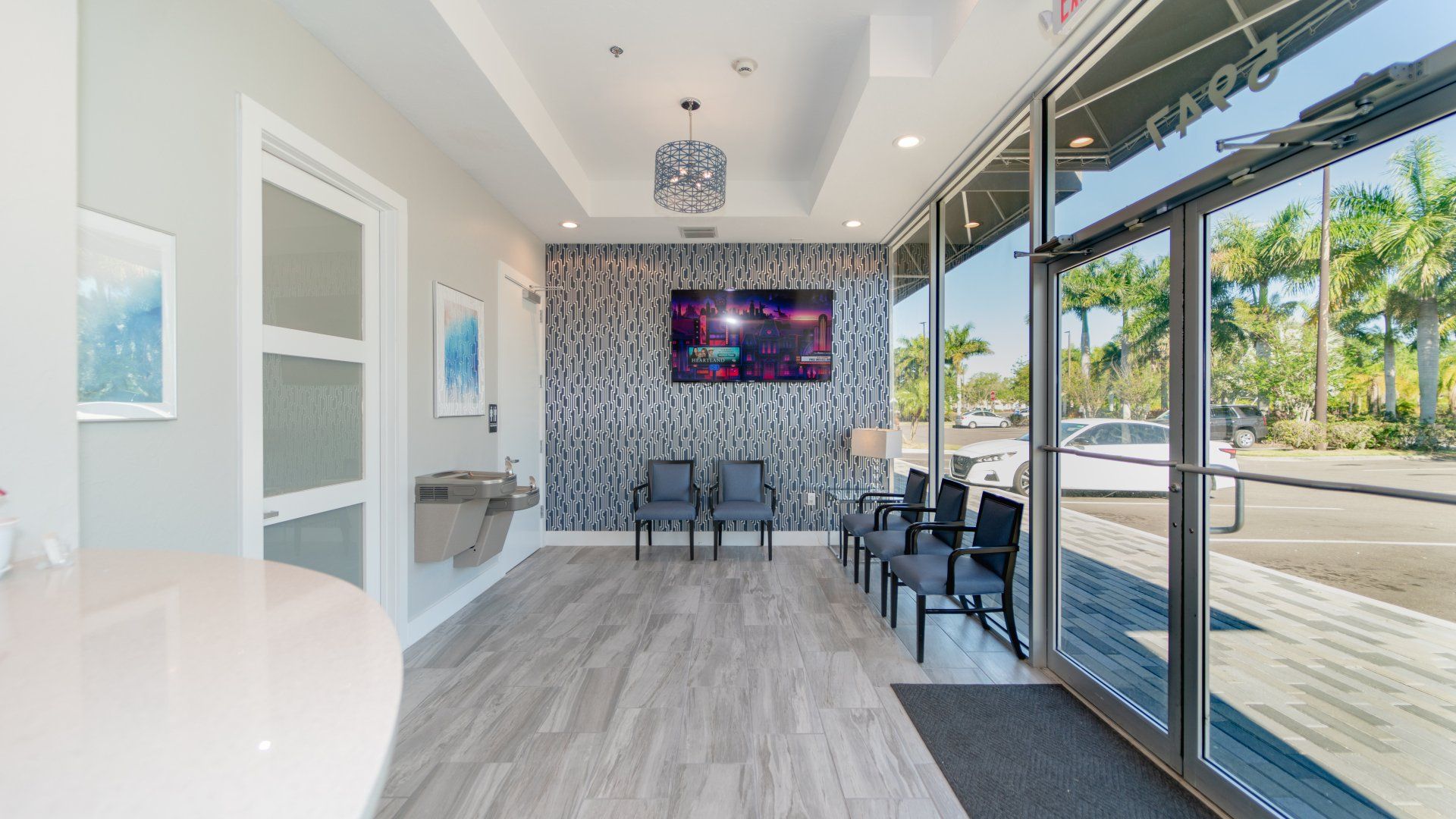 A waiting room at a dental office with chairs and a television.