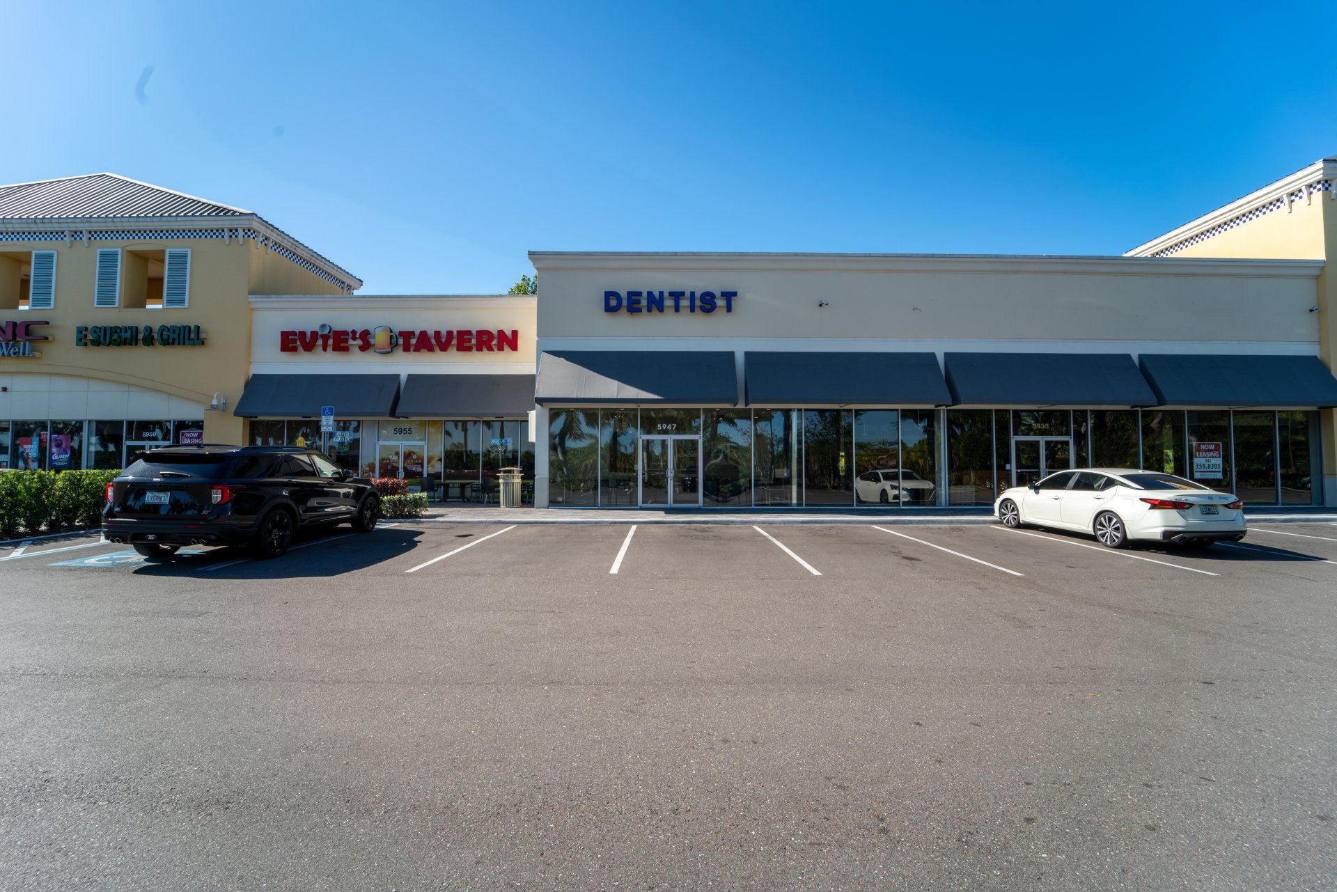 A parking lot with cars parked in front of a building that says dentist.