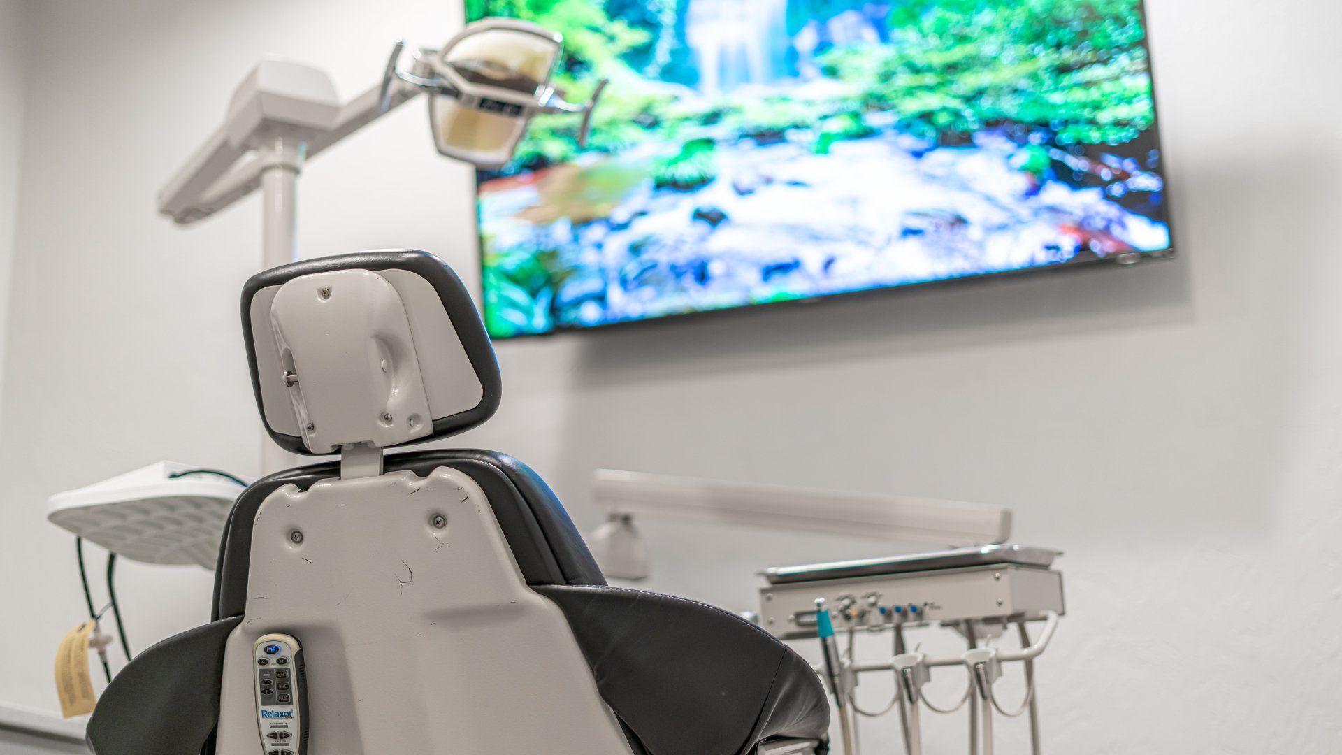 A dental chair is sitting in front of a television in a dental office.