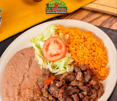 Plate of Mexican food with rice, refried beans, beef, and lettuce with tomato garnish