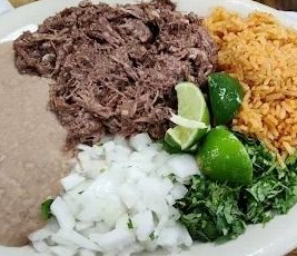 Plate with shredded meat, rice, chopped onions, cilantro, and lime wedges.