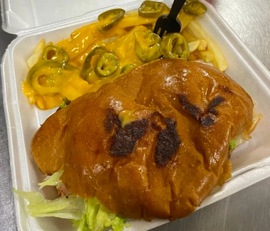 Takeout container with a burger and cheesy jalapeño macaroni salad