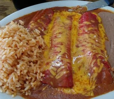 Plate of rice with a cheese-covered enchilada in red sauce