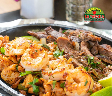 Platter of shrimp and grilled beef with vegetables served in a sizzling skillet