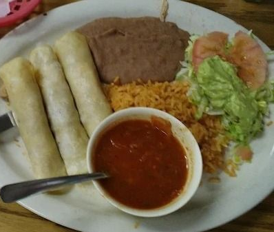 Plate with taquitos, refried beans, rice, salsa, and a small lettuce-tomato salad