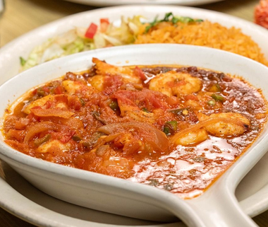 Creamy tomato curry in a white bowl with rice and salad on the side
