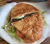 Sandwich on a white plate, cut in half, with lettuce and tomato visible.