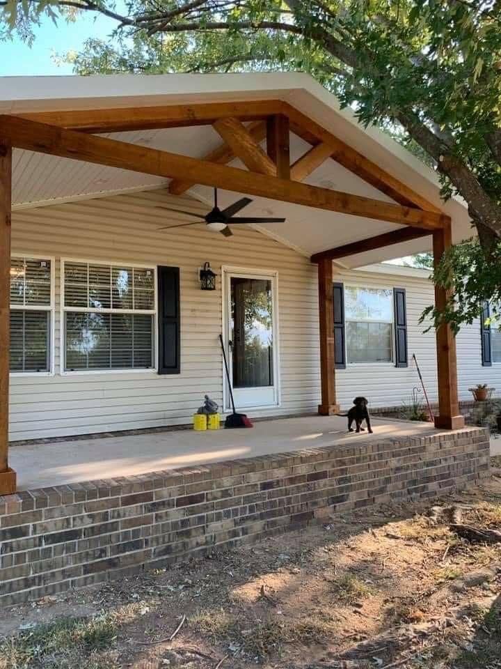 A white house with a wooden porch and a dog on the porch.