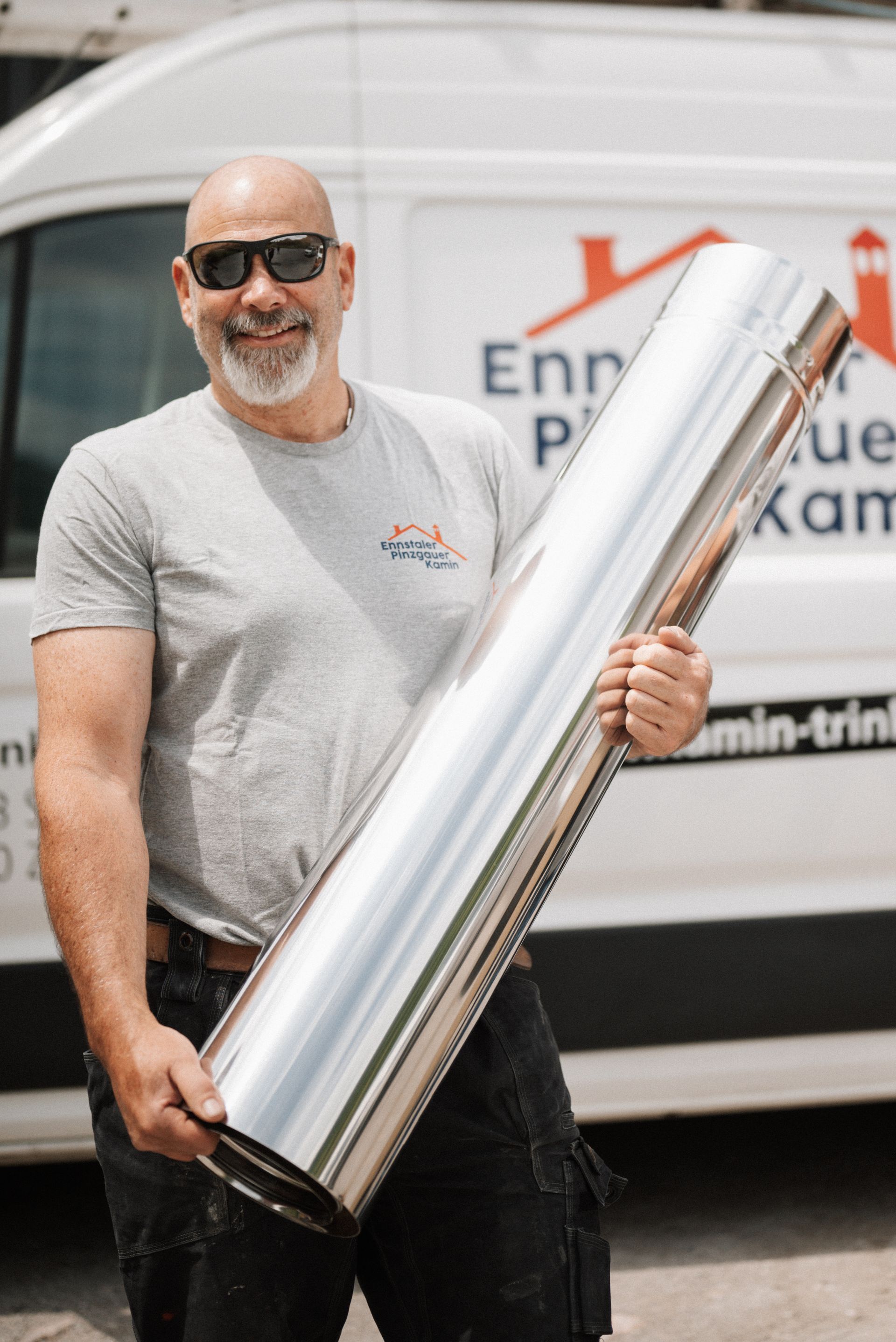 Ein Mann hält ein großes Stück Metall vor einen Lieferwagen.