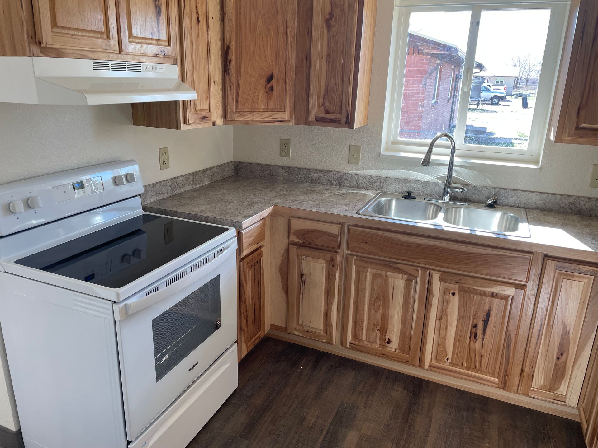Kitchen with light wood cabinets, white appliances, and a window with a view.