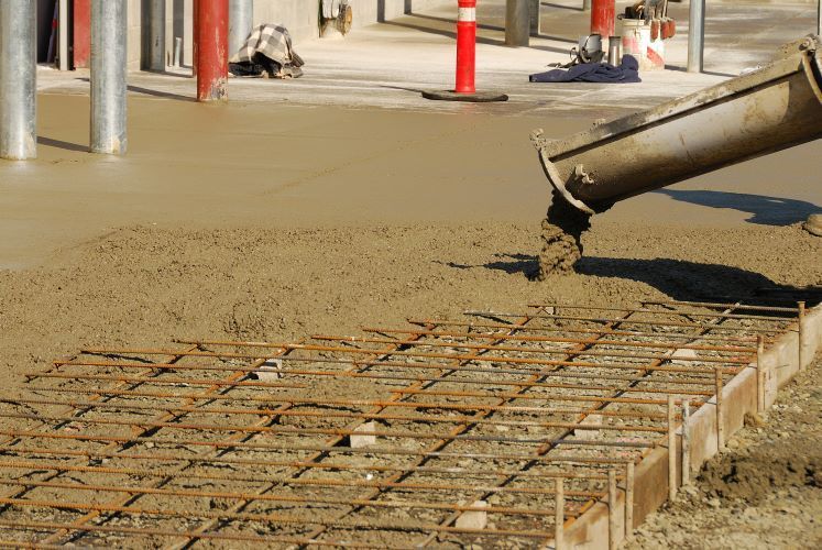 A concrete pump is pouring concrete on a concrete floor.
