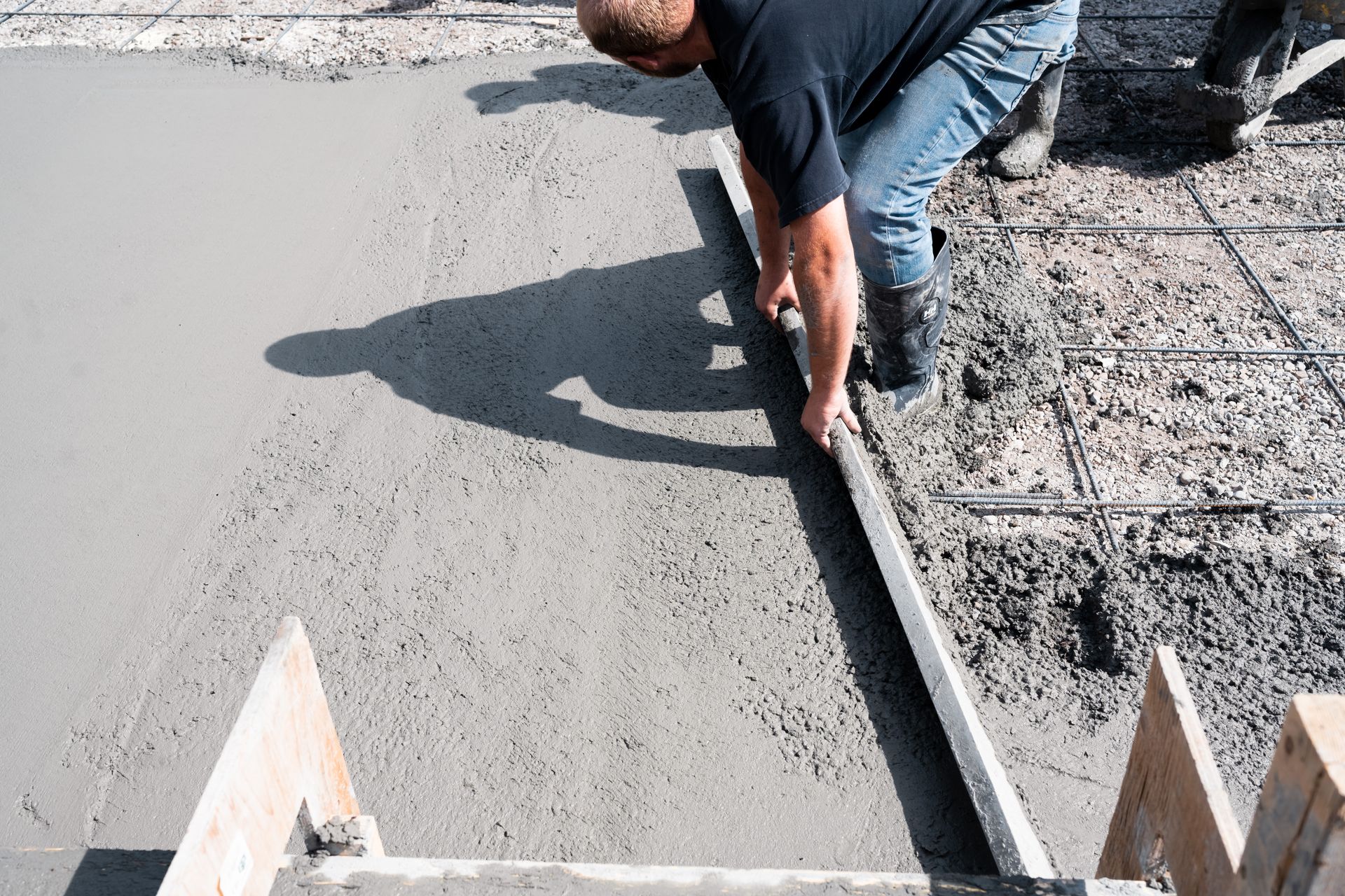 A man is laying concrete on a construction site.