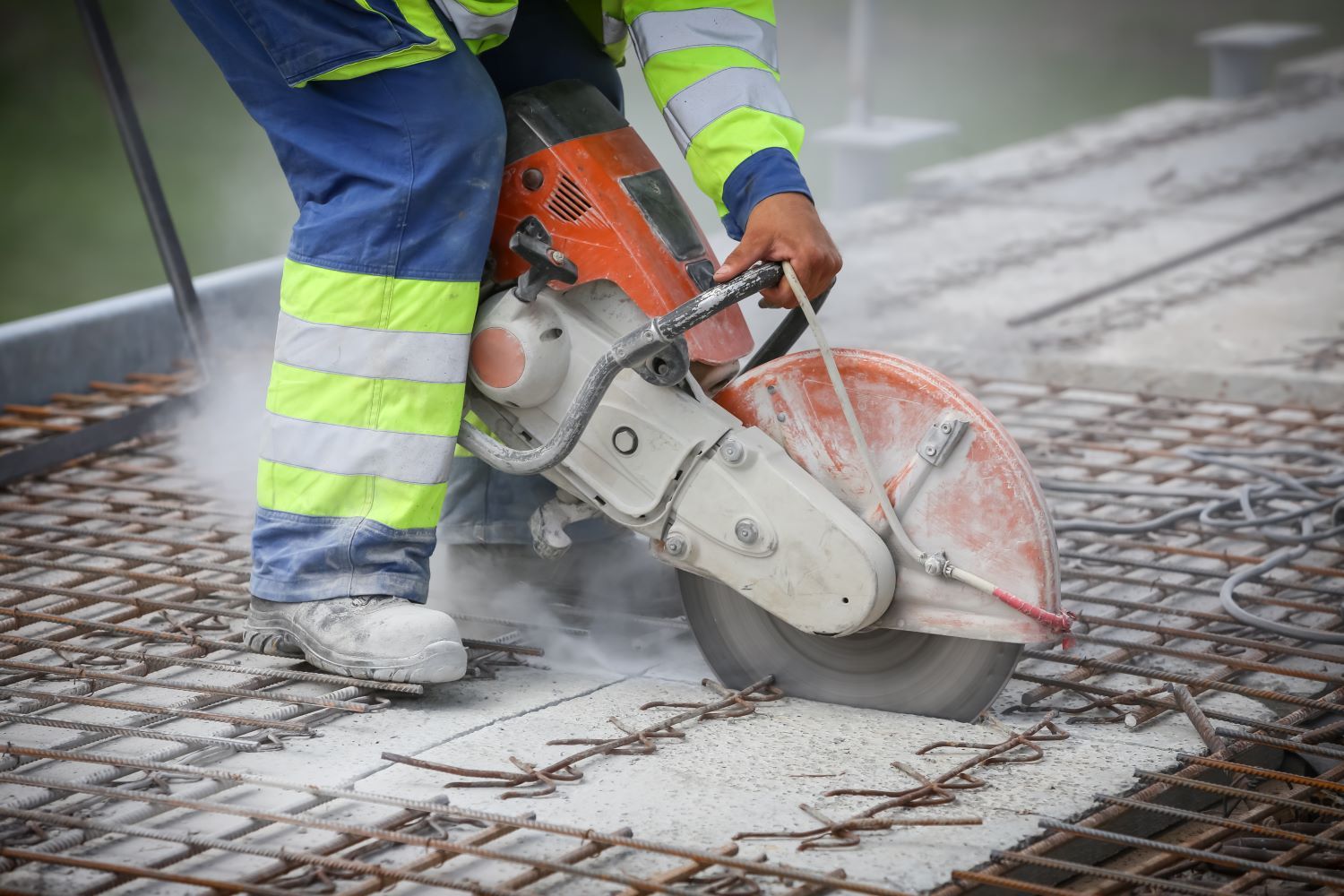 A construction worker is cutting concrete with a circular saw.
