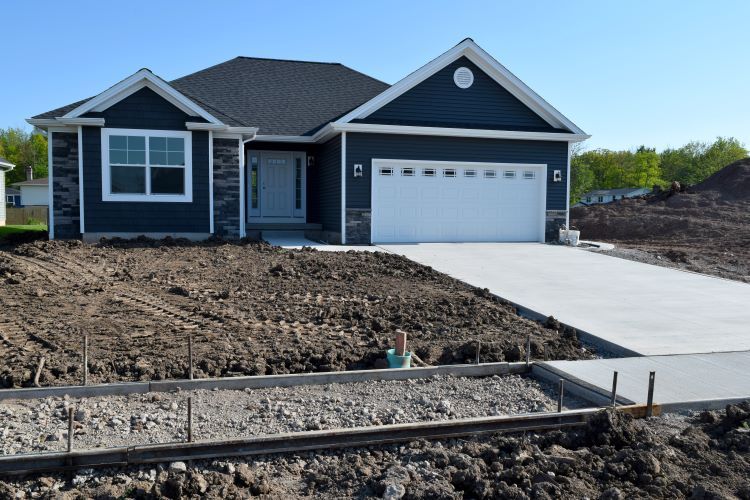 A house that is being built with a lot of dirt in front of it.