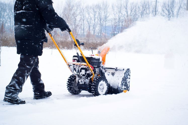 A man is pushing a snow blower through the snow.