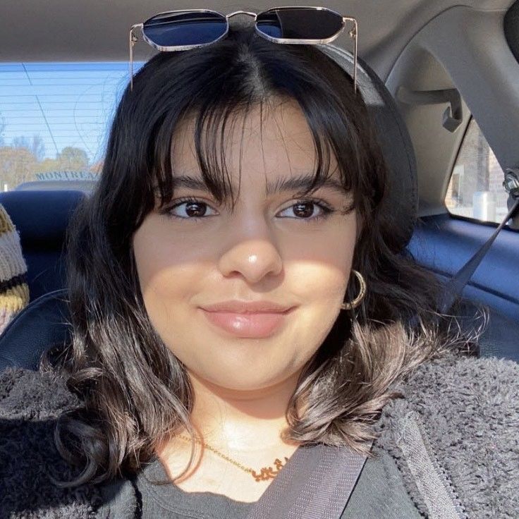 A woman wearing sunglasses is sitting in the back seat of a car.
