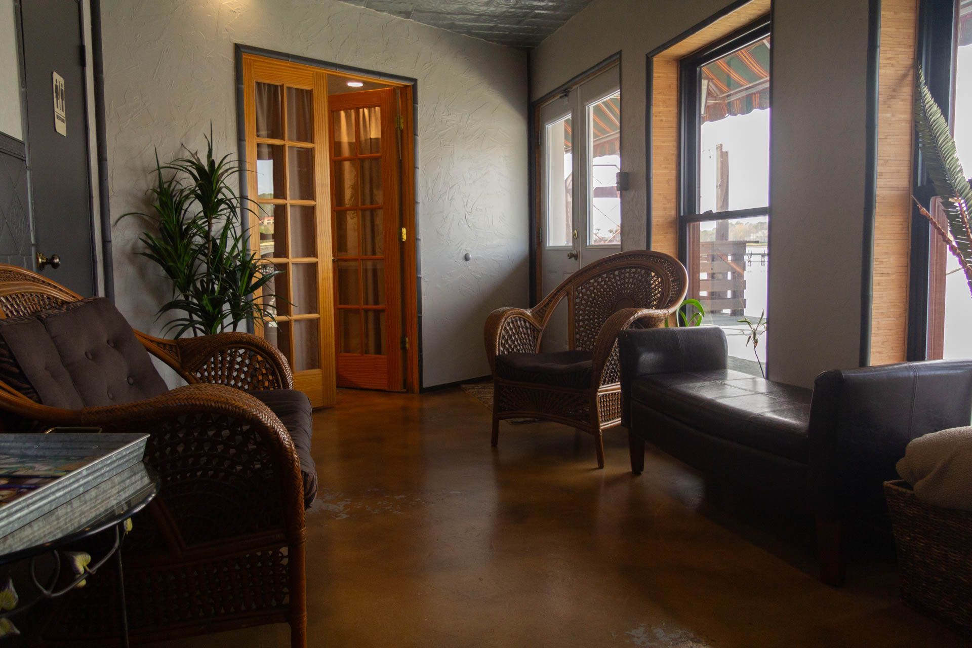 a living room with wicker chairs , a couch , and a table .