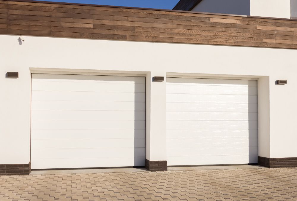 There Are Two White Garage Doors On The Side Of A House — Lighthouse Beach Garage Door Service in Wauchope, NSW