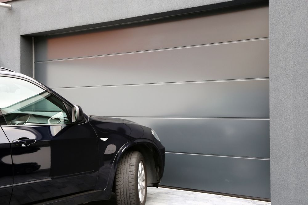 A Black Car Is Parked In Front Of A Garage Door — Lighthouse Beach Garage Door Service in Port Macquarie, NSW
